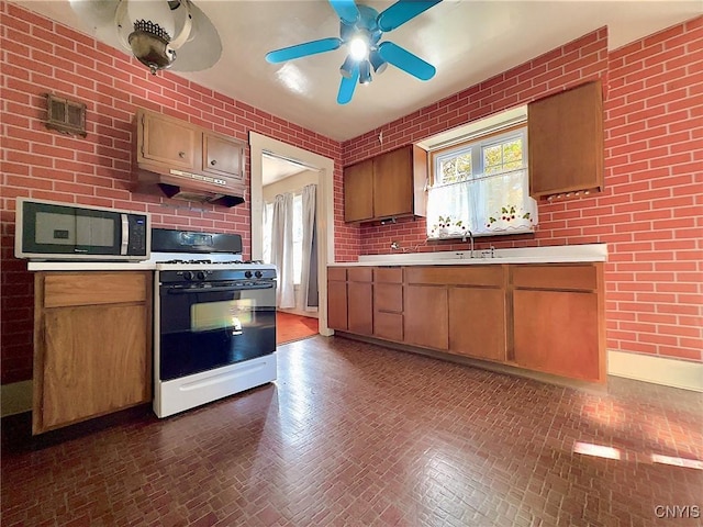 kitchen with ceiling fan, white gas range, and sink