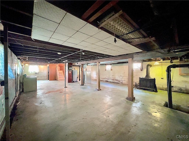 basement featuring a healthy amount of sunlight, washer / dryer, a wood stove, and gas water heater