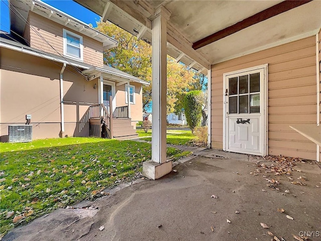 doorway to property with central AC unit and a yard