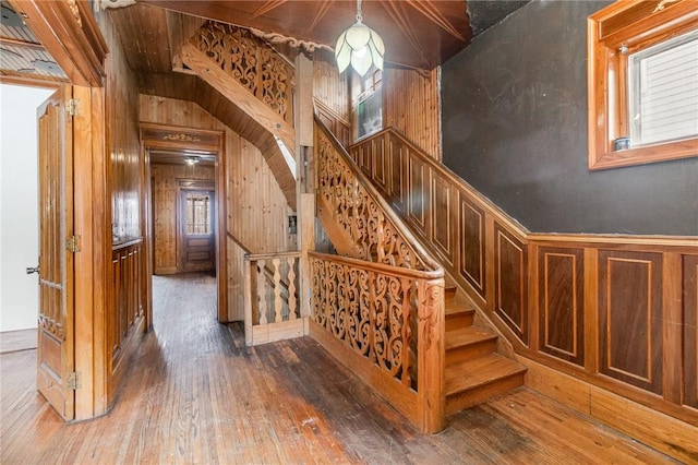 stairway with hardwood / wood-style floors, a healthy amount of sunlight, and wood walls