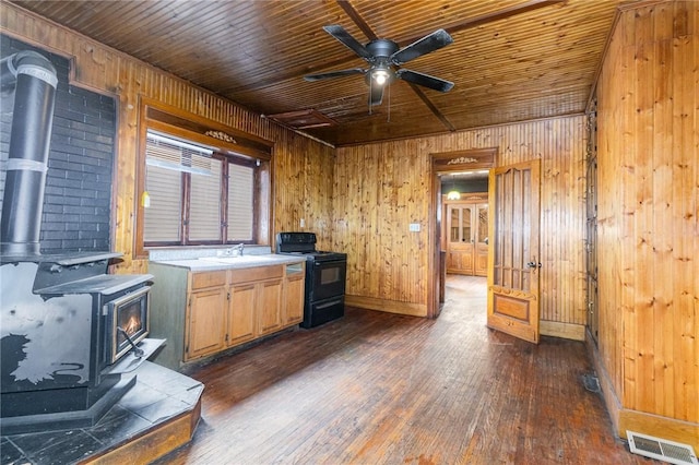 kitchen with a wood stove, ceiling fan, black electric range oven, wood walls, and wood ceiling