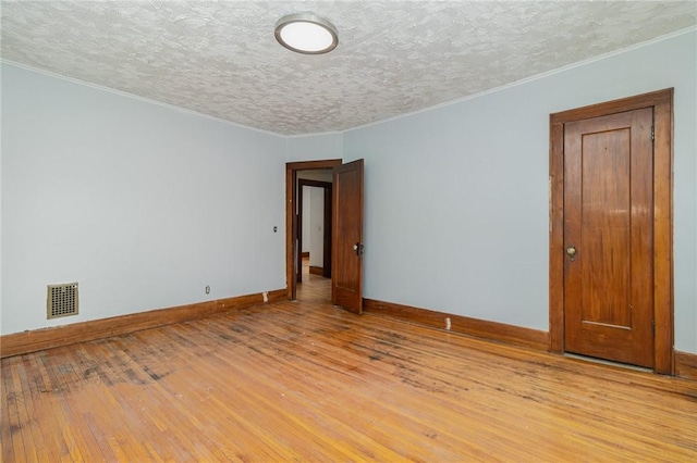 unfurnished room featuring light hardwood / wood-style flooring and a textured ceiling