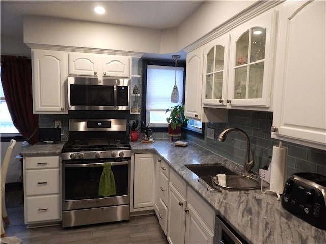 kitchen with tasteful backsplash, stainless steel appliances, sink, decorative light fixtures, and white cabinets