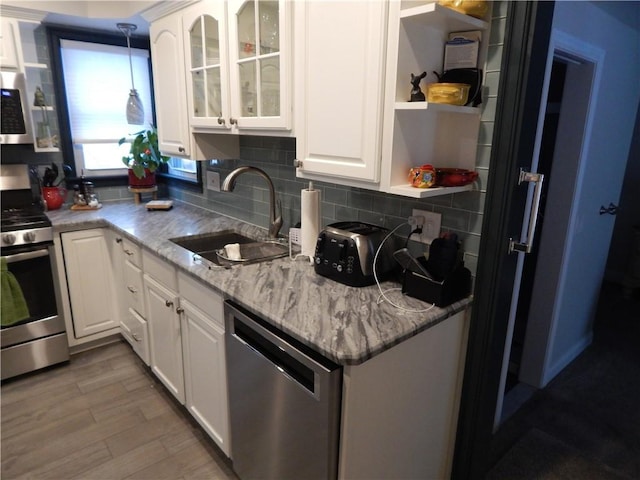 kitchen with appliances with stainless steel finishes, tasteful backsplash, sink, decorative light fixtures, and white cabinets