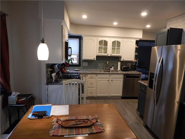 kitchen with white cabinets, sink, decorative backsplash, appliances with stainless steel finishes, and decorative light fixtures