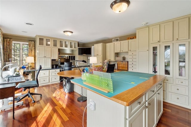 kitchen with hardwood / wood-style floors, a kitchen island, and cream cabinets