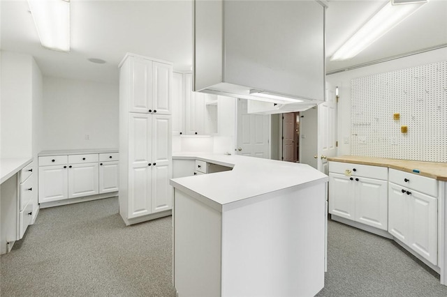 kitchen featuring white cabinets, wooden counters, kitchen peninsula, and a kitchen island