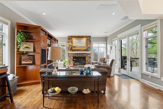 living room featuring hardwood / wood-style flooring, a fireplace, crown molding, and french doors