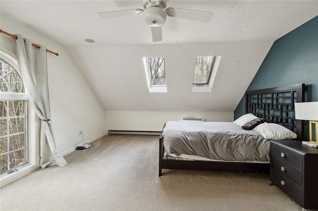 bedroom with carpet flooring, ceiling fan, a baseboard heating unit, and vaulted ceiling with skylight