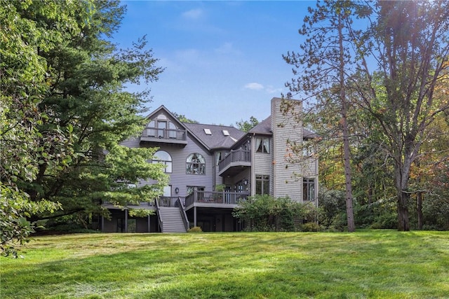 rear view of house featuring a lawn and a deck