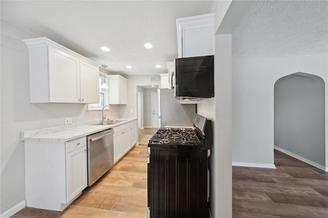 kitchen with white cabinetry, sink, light hardwood / wood-style floors, and appliances with stainless steel finishes