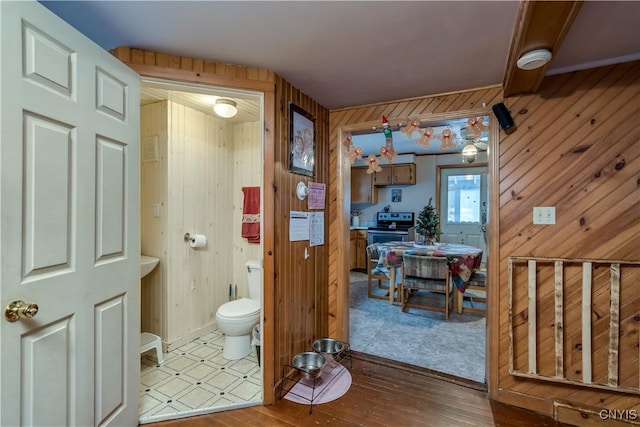 bathroom featuring wooden walls and toilet