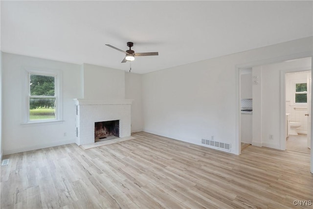 unfurnished living room with ceiling fan, light hardwood / wood-style flooring, and a brick fireplace