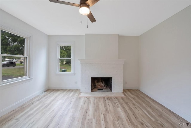 unfurnished living room with ceiling fan, light hardwood / wood-style floors, and a brick fireplace