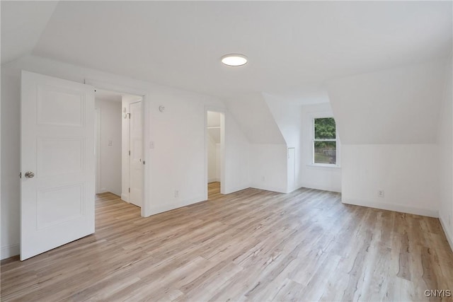 additional living space with light wood-type flooring and vaulted ceiling