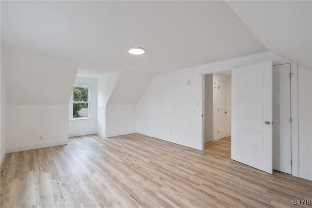 additional living space with light hardwood / wood-style floors and lofted ceiling