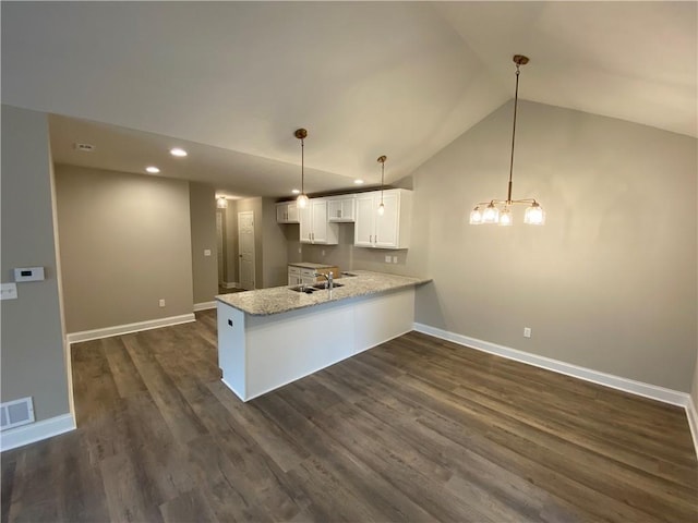 kitchen with lofted ceiling, white cabinets, sink, decorative light fixtures, and kitchen peninsula