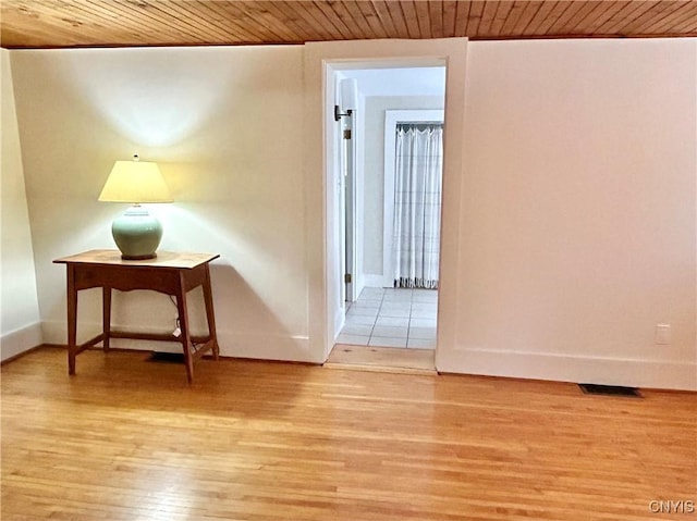 corridor featuring light wood-type flooring and wood ceiling