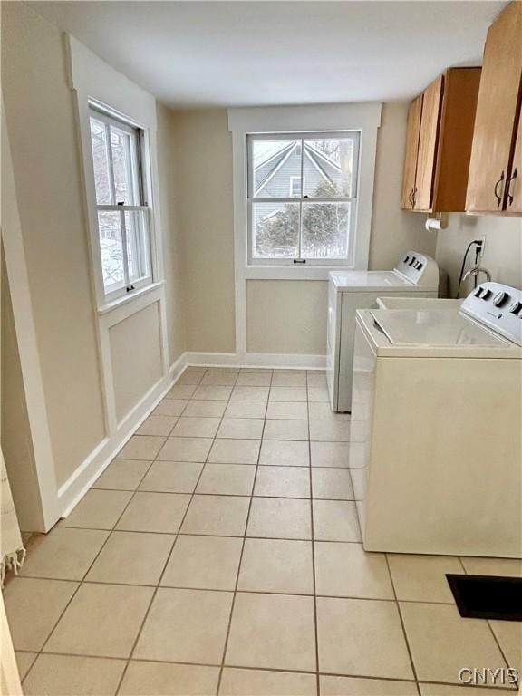 laundry room featuring cabinets, light tile patterned floors, and independent washer and dryer