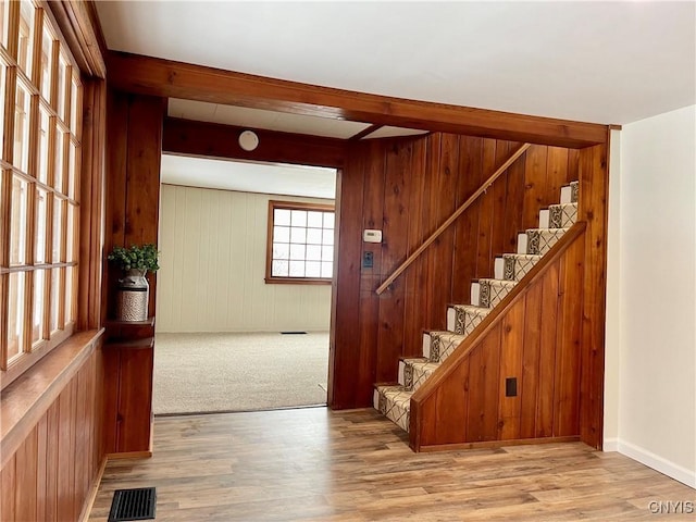 entrance foyer with beamed ceiling, light wood-type flooring, and wooden walls