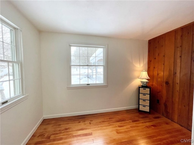 unfurnished room with wood walls and hardwood / wood-style flooring