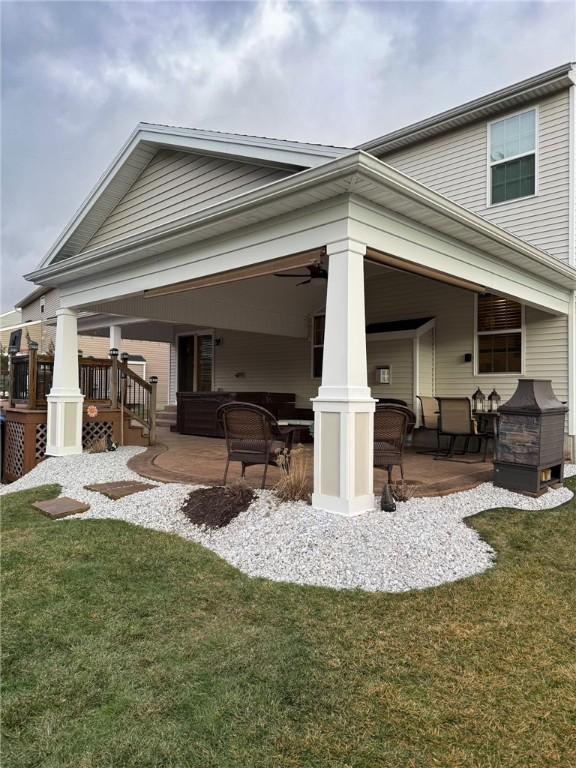 rear view of property with ceiling fan, a patio area, and a lawn