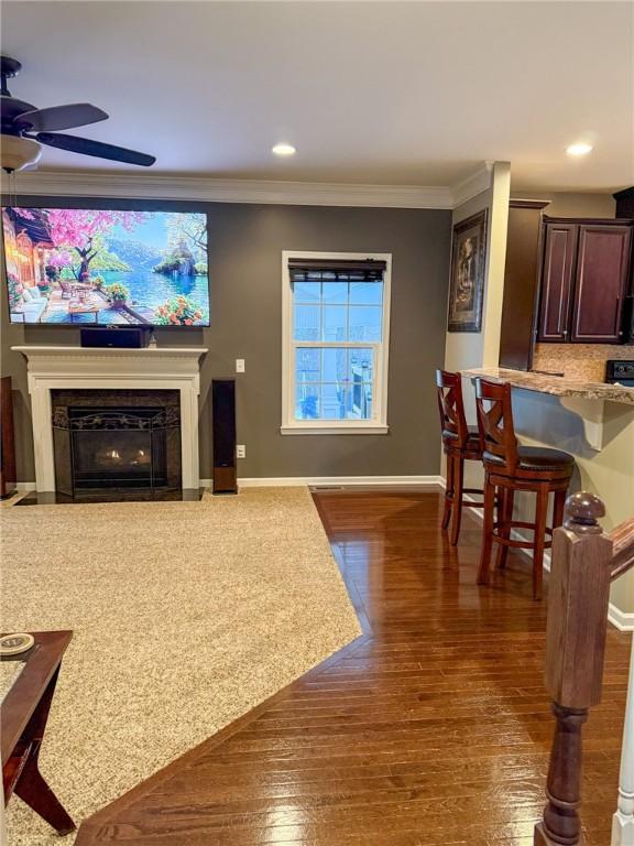 living room with dark hardwood / wood-style floors, ceiling fan, and crown molding