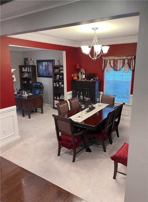 dining space with carpet floors, a chandelier, and ornamental molding