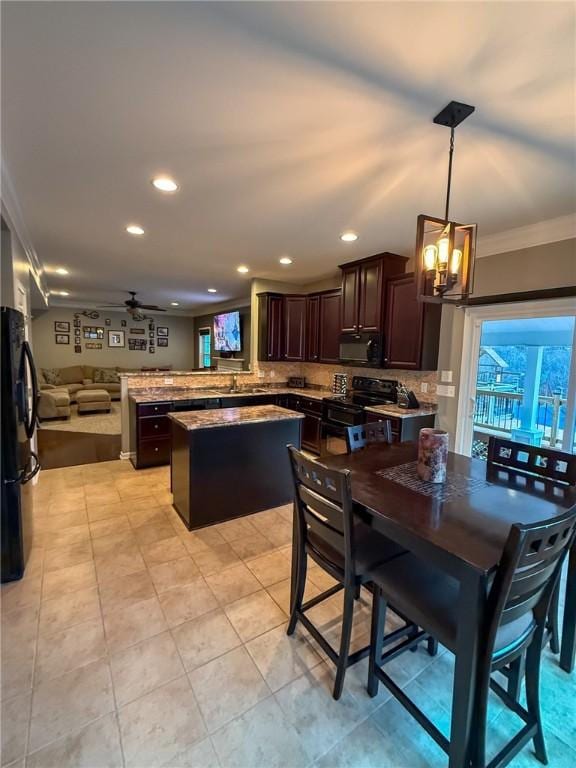 kitchen with kitchen peninsula, pendant lighting, a kitchen island, black appliances, and ceiling fan with notable chandelier