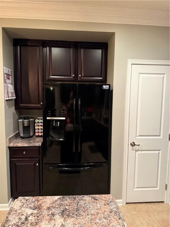 kitchen with crown molding, light stone counters, dark brown cabinets, light tile patterned flooring, and black fridge with ice dispenser