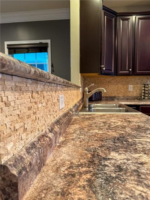 kitchen featuring dark brown cabinetry, crown molding, and sink