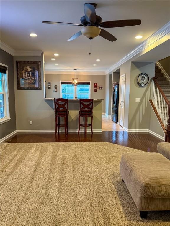 interior space featuring ceiling fan with notable chandelier, dark hardwood / wood-style flooring, and crown molding