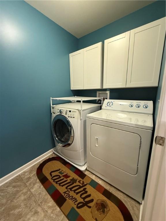 clothes washing area with washing machine and clothes dryer and cabinets