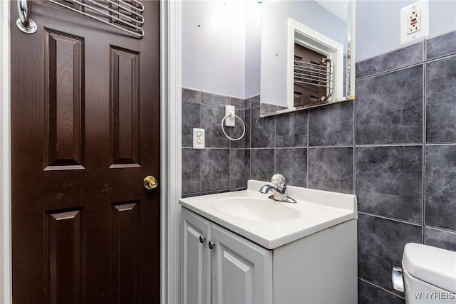 bathroom featuring vanity, toilet, and tile walls