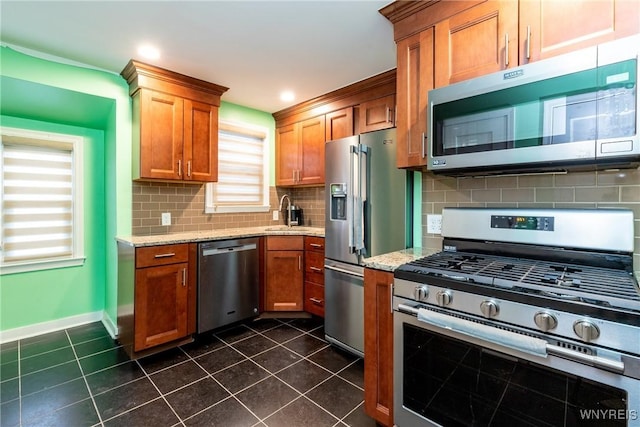 kitchen featuring dark tile patterned flooring, sink, decorative backsplash, light stone countertops, and stainless steel appliances