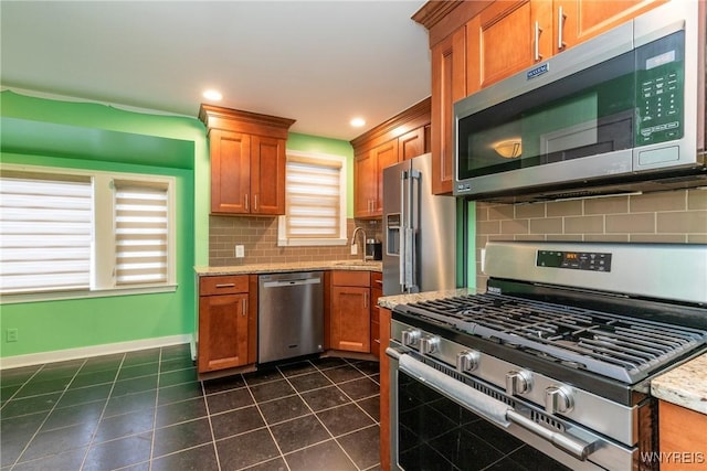 kitchen featuring appliances with stainless steel finishes, backsplash, light stone counters, and sink