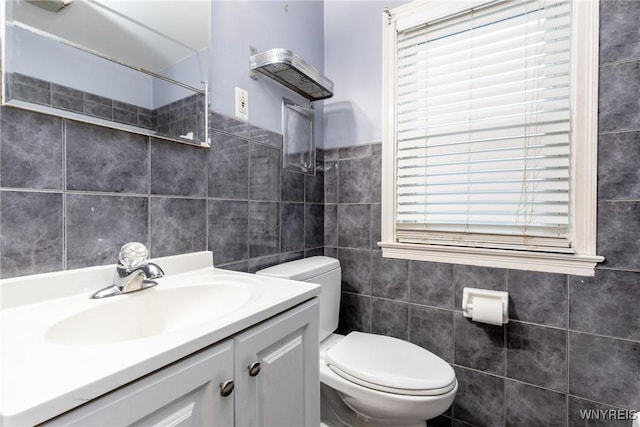 bathroom featuring vanity, toilet, and tile walls