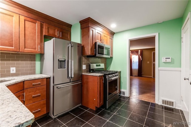 kitchen featuring decorative backsplash, appliances with stainless steel finishes, and light stone counters