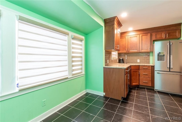 kitchen with decorative backsplash, high end fridge, and light stone counters