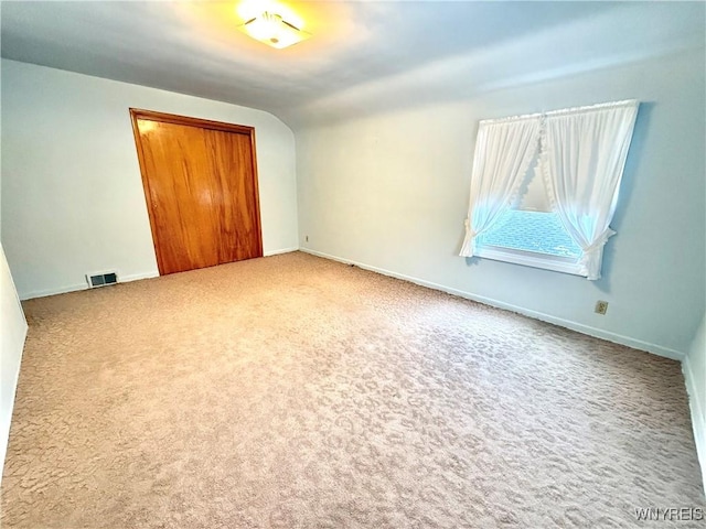 unfurnished bedroom featuring carpet flooring, vaulted ceiling, and a closet