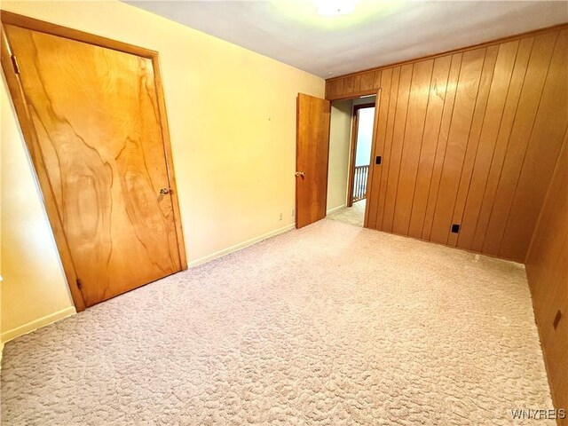 empty room with wooden walls and light colored carpet