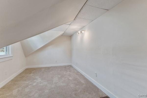 additional living space with light colored carpet and vaulted ceiling