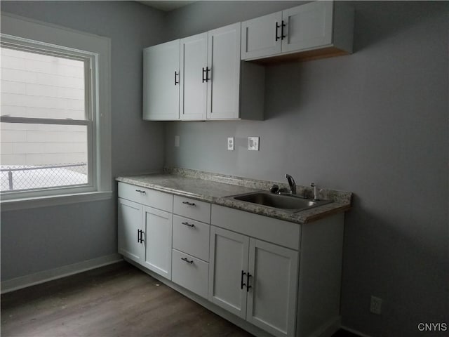 kitchen with dark hardwood / wood-style flooring, white cabinetry, and sink