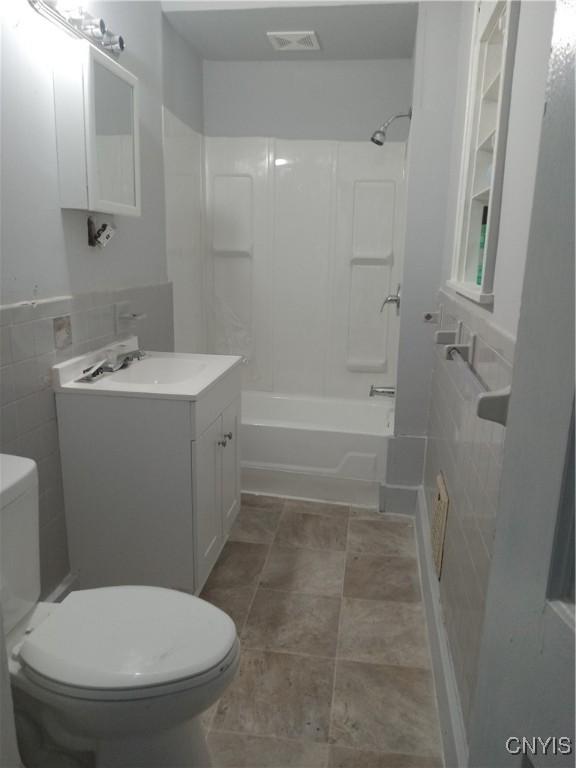 full bathroom with vanity, toilet, tile walls, and shower / washtub combination