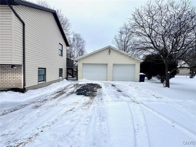 snow covered property featuring an outbuilding and a garage