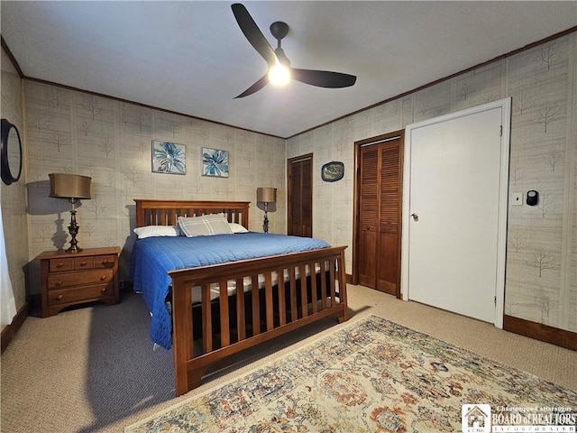 carpeted bedroom featuring ceiling fan, crown molding, and two closets