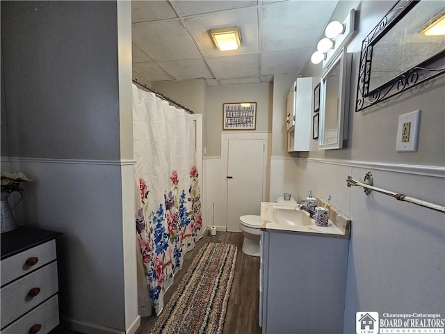 bathroom featuring a paneled ceiling, vanity, hardwood / wood-style flooring, toilet, and walk in shower