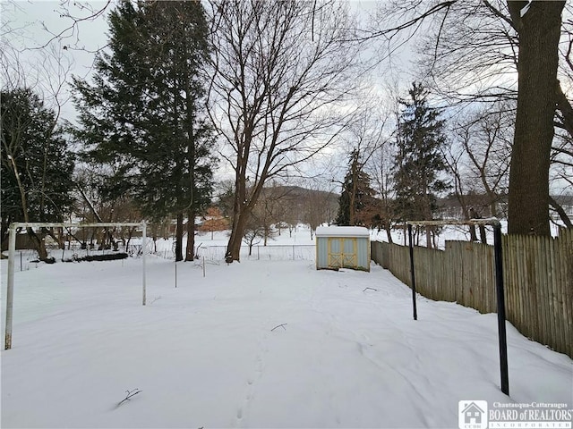 snowy yard featuring a storage unit