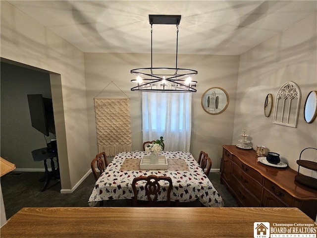 dining space with a chandelier and dark colored carpet