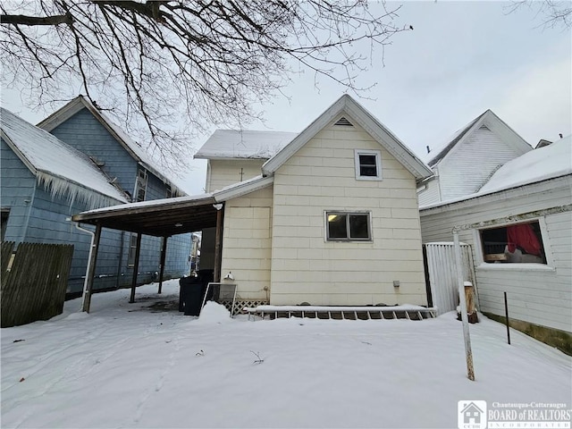 snow covered rear of property featuring a carport